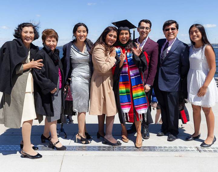 A family with their graduate, posing lakeside