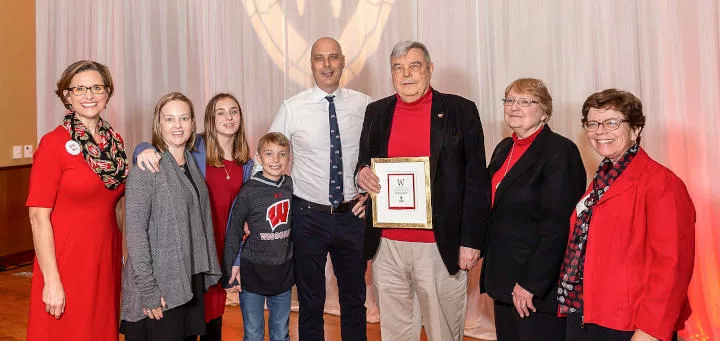 Dennis Maki holding an award, with his family and the chancellor