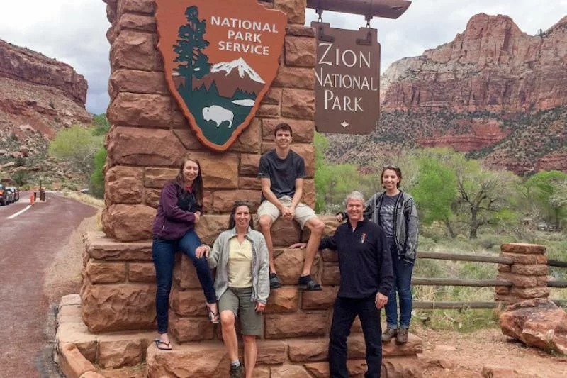 Mary Landry and family in front of a Zion National Park sign