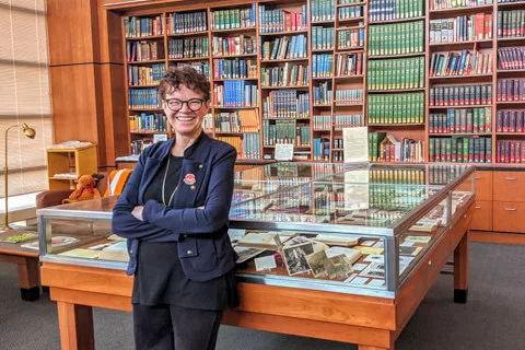 A librarian smiling at the camera inside of a library