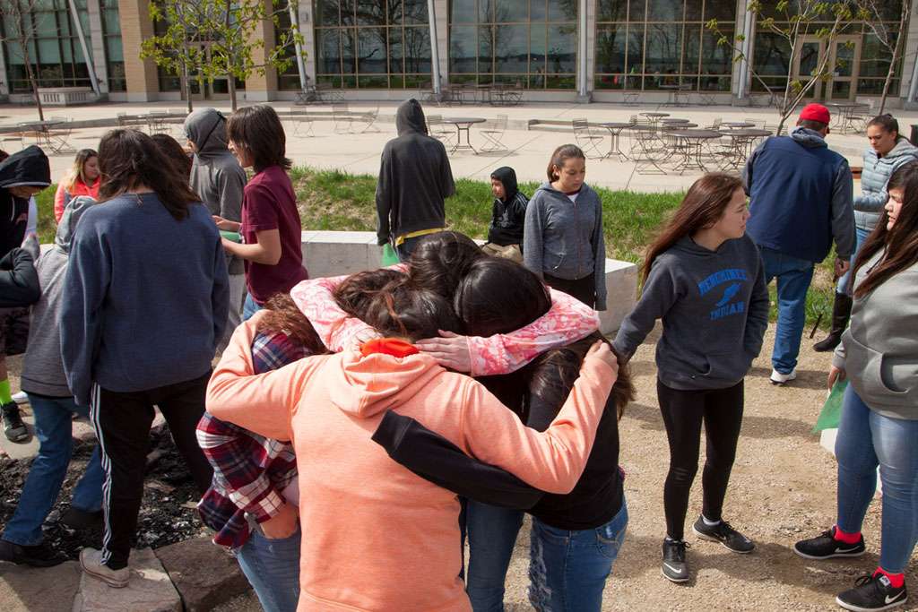 Four middle or high school students in a huddle as part of a team building activity